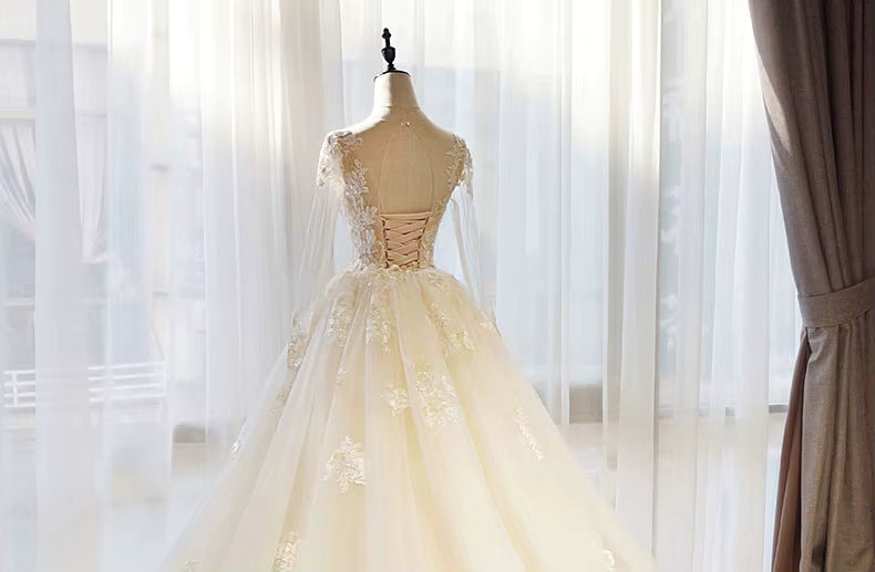 Elegant beige evening gown on a mannequin against a soft, blurred background