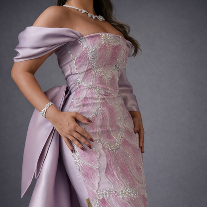 Pink evening gown with intricate detailing on a gray background