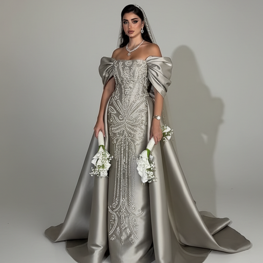 Woman wearing a silver evening gown with intricate detailing on a plain background