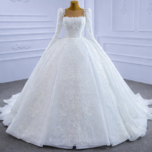 White lace wedding dress on a mannequin against a white wall.