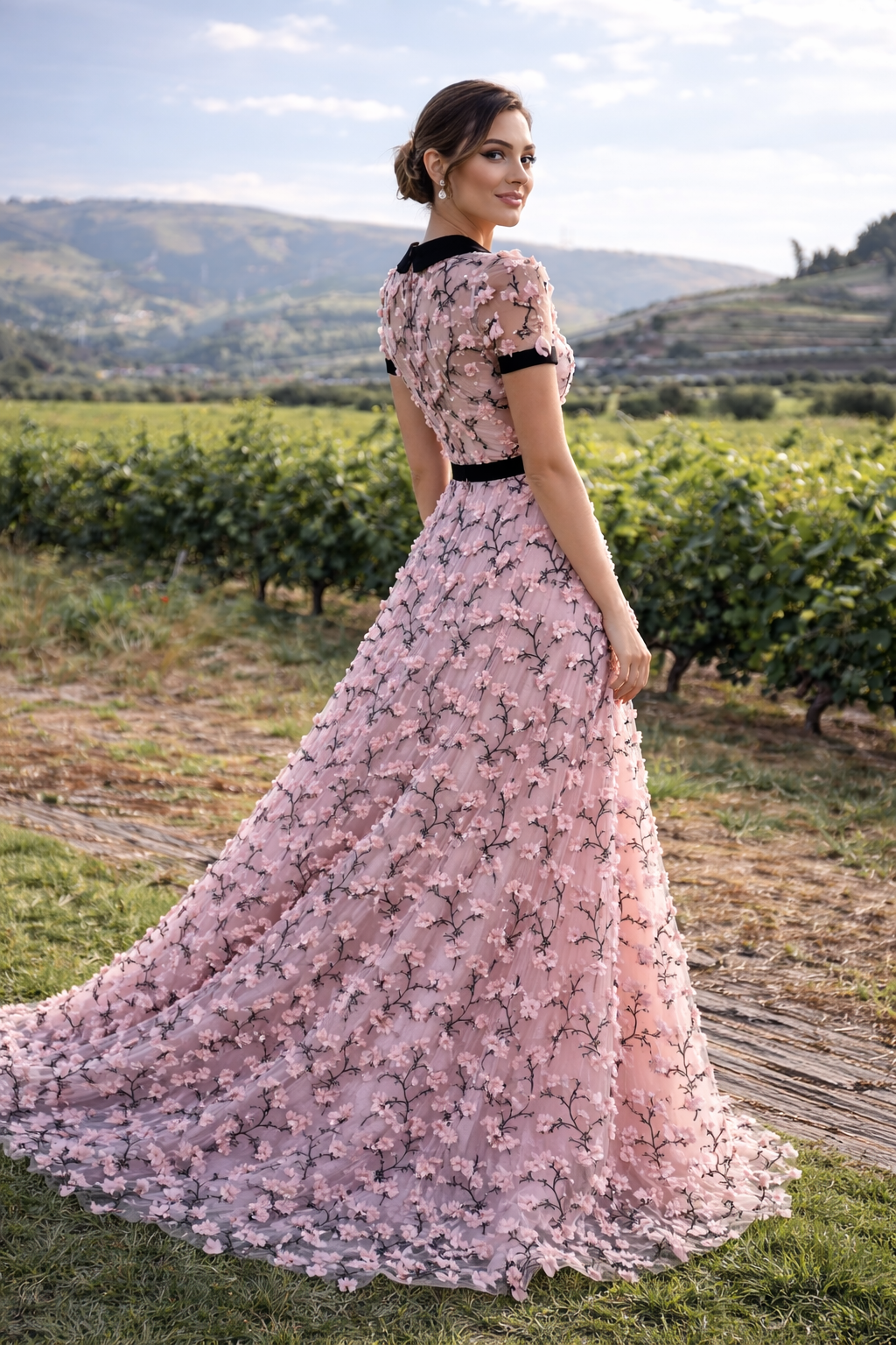 Woman in a pink floral dress standing in a vineyard