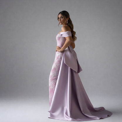 Woman wearing a pink evening gown with a long train on a gray background