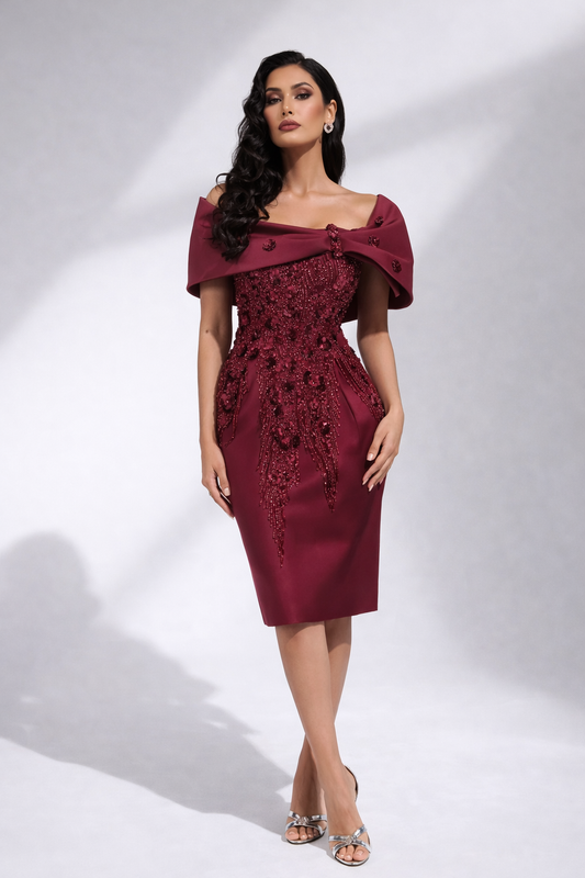 Woman wearing a burgundy dress with floral embroidery on a white background