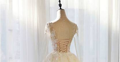 Mannequin wearing a beige evening gown with lace details against a soft white curtain background