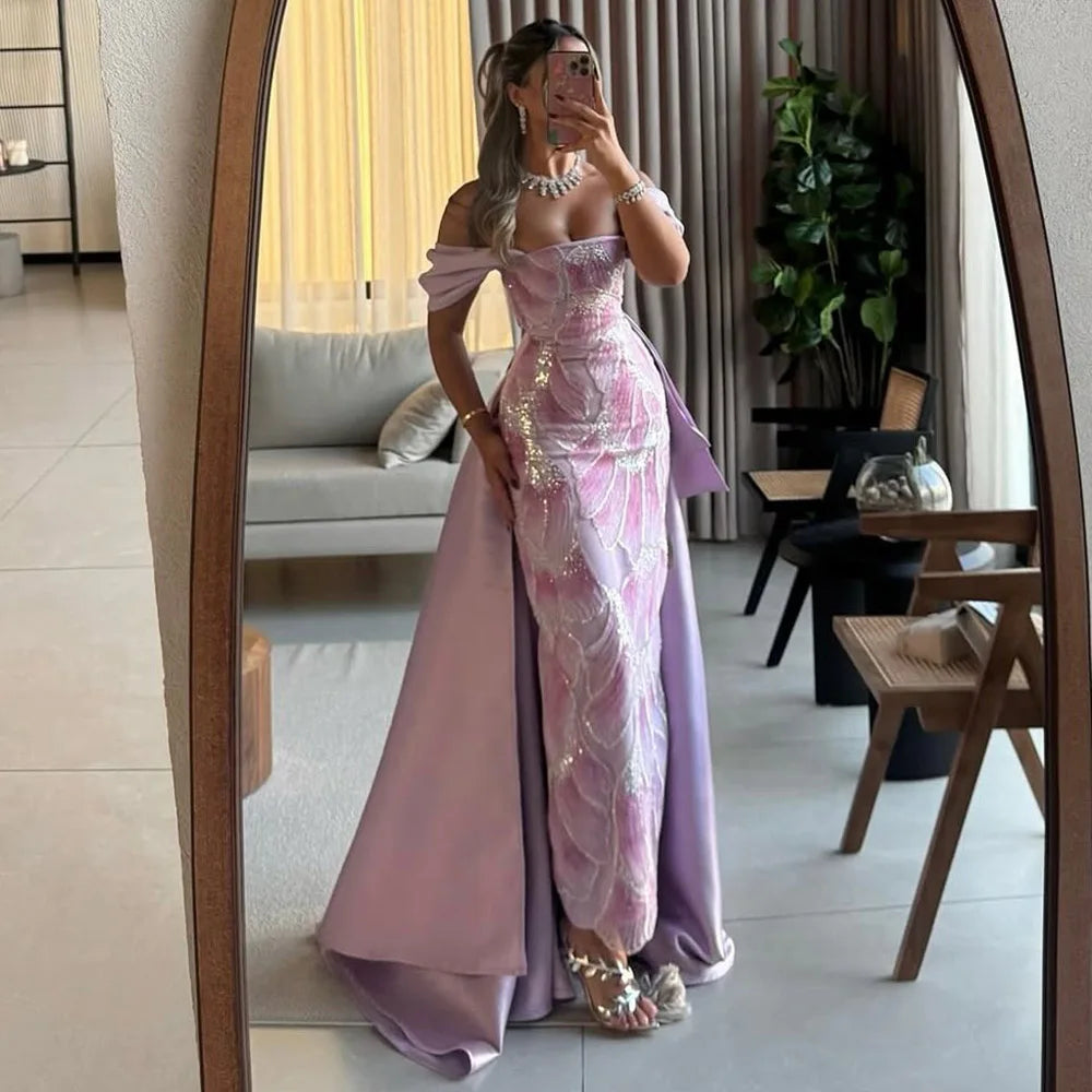 Woman in a pink and purple evening gown taking a mirror selfie in a stylish room.