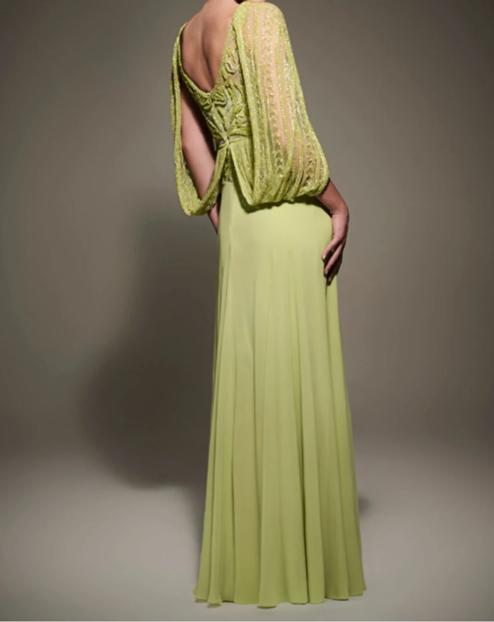 Woman wearing a green evening gown with a textured top against a neutral background
