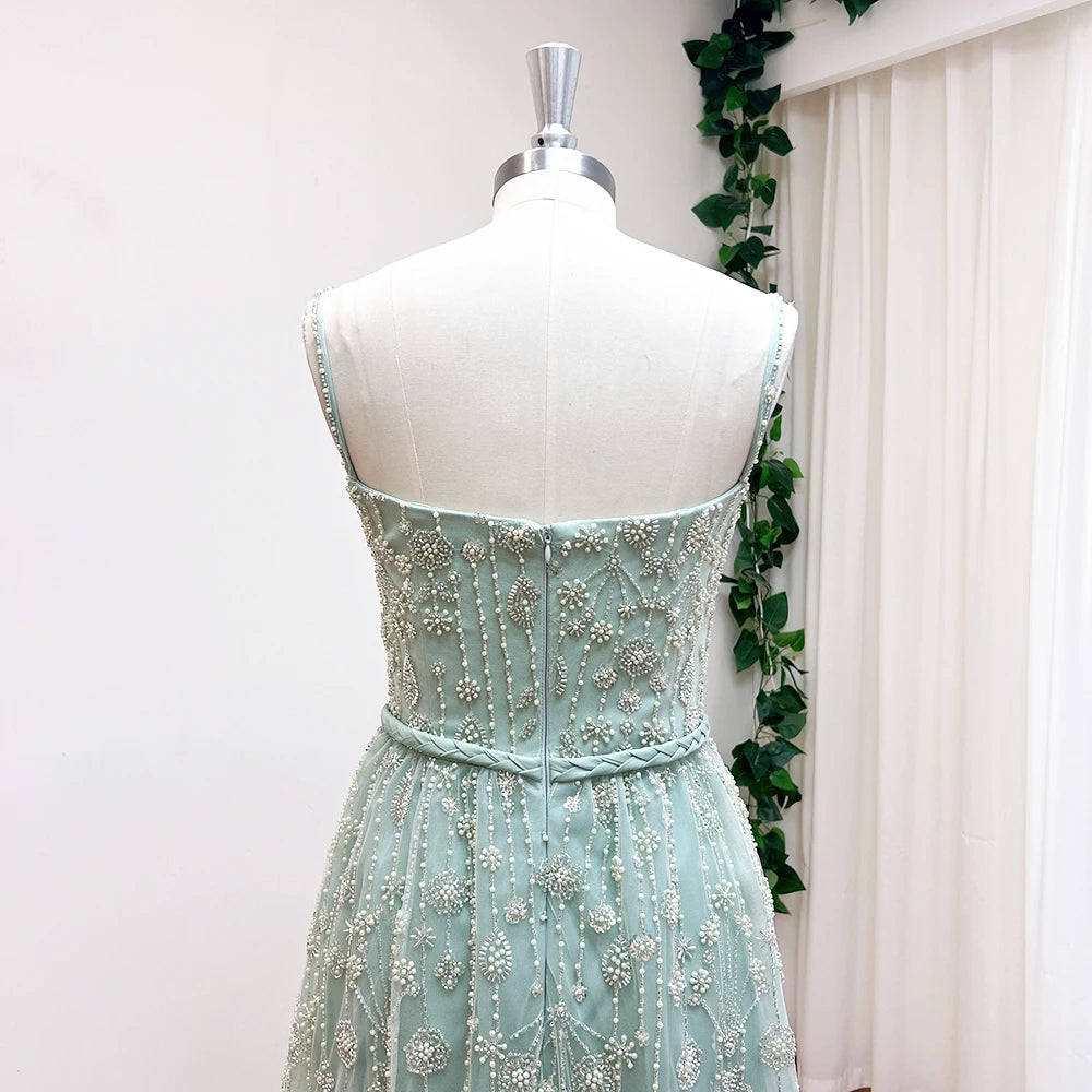 Mint green beaded dress on a mannequin against a white curtain background