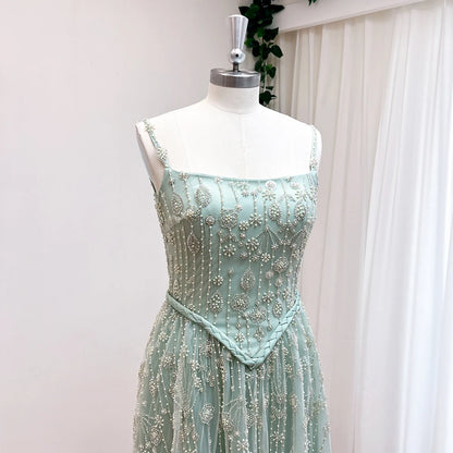 Mint green beaded dress on a mannequin against a white curtain background