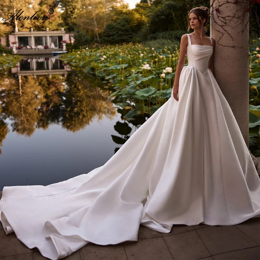 Woman in a white wedding dress standing by a pond with greenery