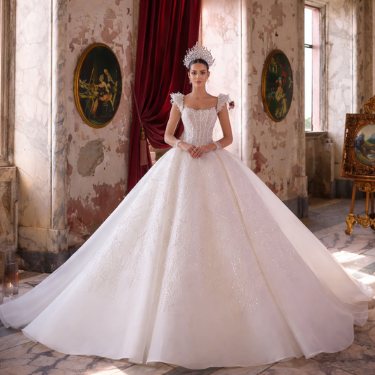Woman in a white wedding dress standing in an ornate room with red curtains and decorative paintings.
