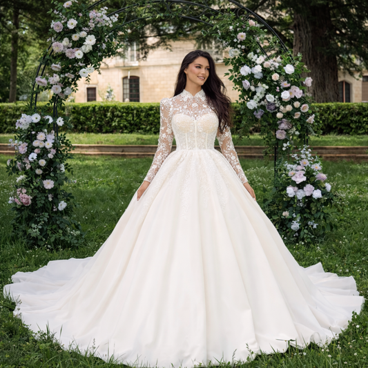 Woman in a white wedding dress standing under a floral archway in a garden setting.