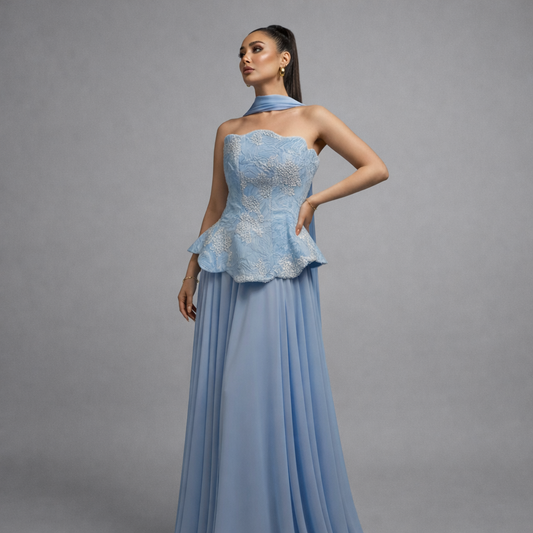 Woman wearing a light blue evening gown with a textured bodice against a gray background