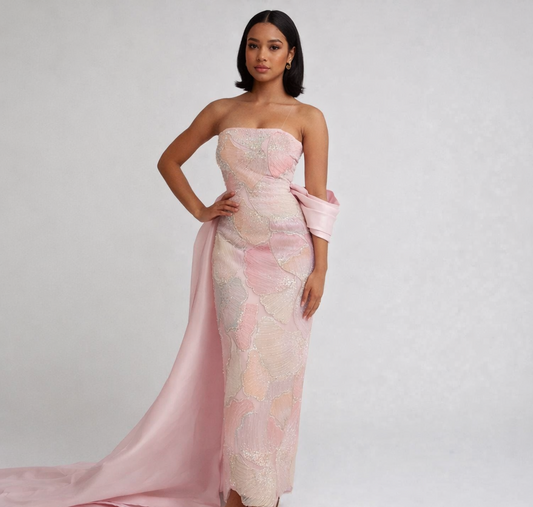 Woman wearing a pink strapless gown with a long train on a white background