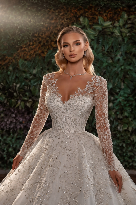 Woman wearing a sparkling wedding dress with long sleeves against a blurred natural background
