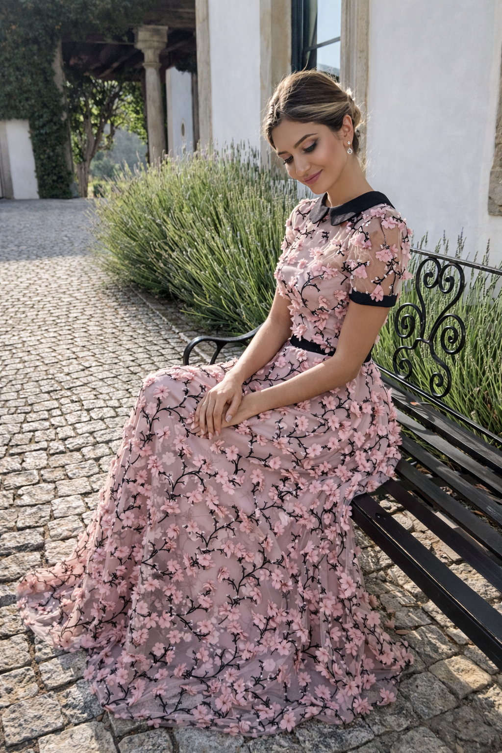 Woman in a pink floral dress sitting on a bench outdoors.