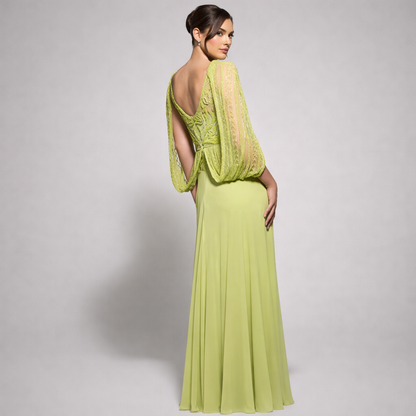 Woman wearing a light green evening gown with a sheer overlay on a gray background